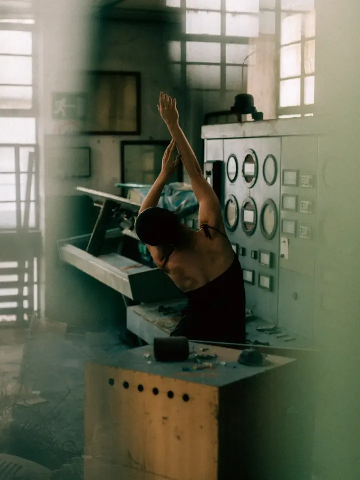 Woman with raised arms in an old factory control room