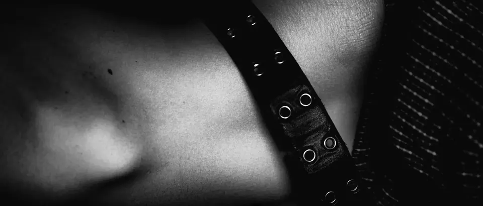 Close-up of skin and a studded leather strap