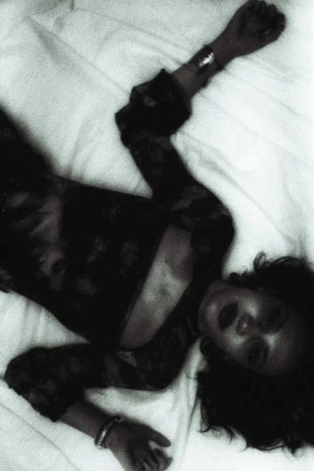 Woman in black lace lying on white sheets, overhead portrait